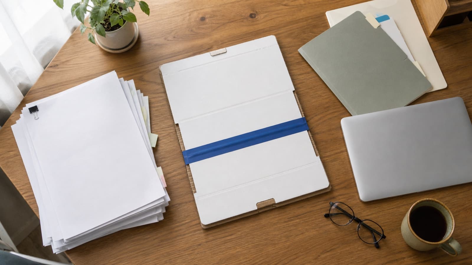 Microsoft 365からGoogle Workspaceへ、書類の入った引っ越し箱が机の上をゆっくり移されていくフラットレイイメージ